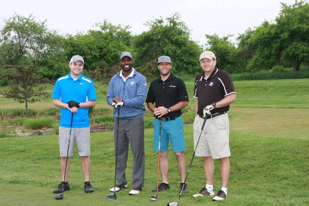 Four men with golf clubs on a golf course